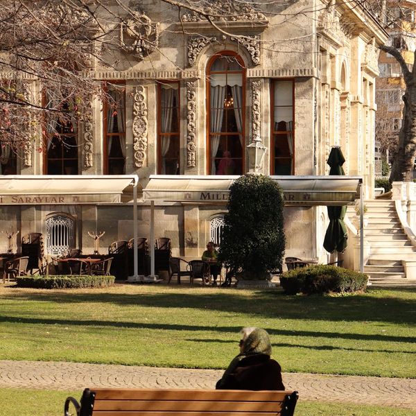 A person walking briskly through a city park on a sunny day.