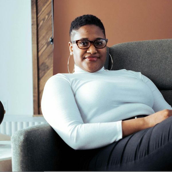 Person sitting peacefully with eyes closed in a brightly lit room.